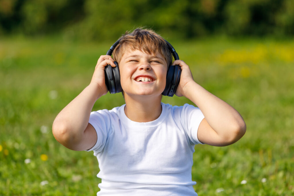boy with headphones listening to music while sitting on the grass